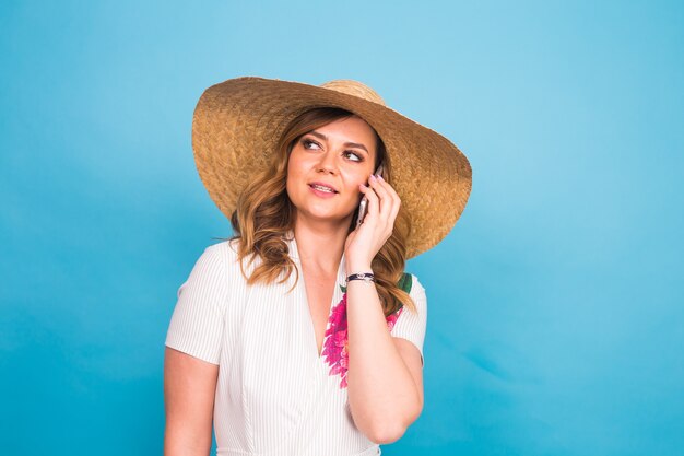 Donna femminile sorridente che parla sul telefono su un fondo blu.