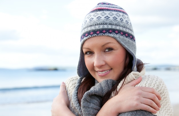 Donna fredda con sciarpa e cappello colorato in piedi sulla spiaggia