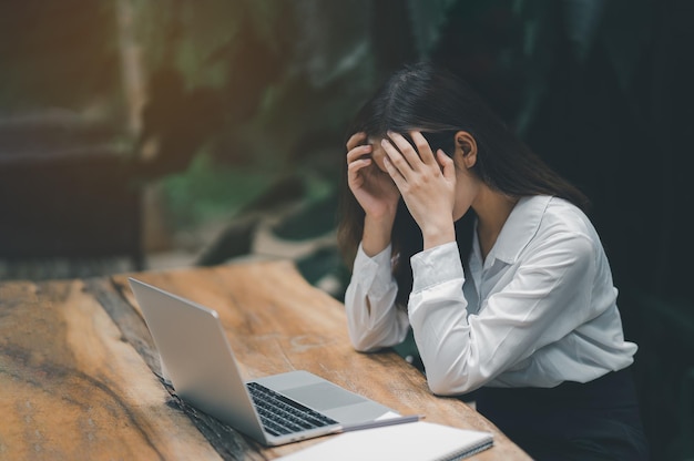 Donna freelance asiatica mano sopra la testa con depressione stressante tempo triste mentre si lavora al computer portatile a casa Depressione donna triste serios lavorando da casa Lavorare ovunque concetto