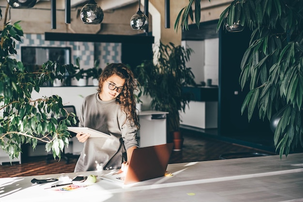 Donna freelance che usa il portatile in un comodo ufficio verde in un luogo di lavoro moderno