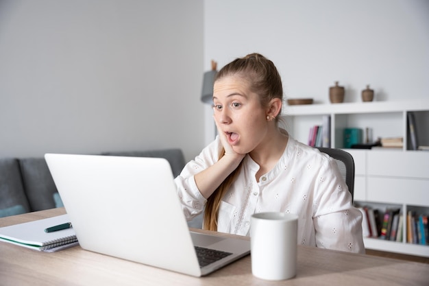 Donna freelance sorpresa che esamina il computer portatile