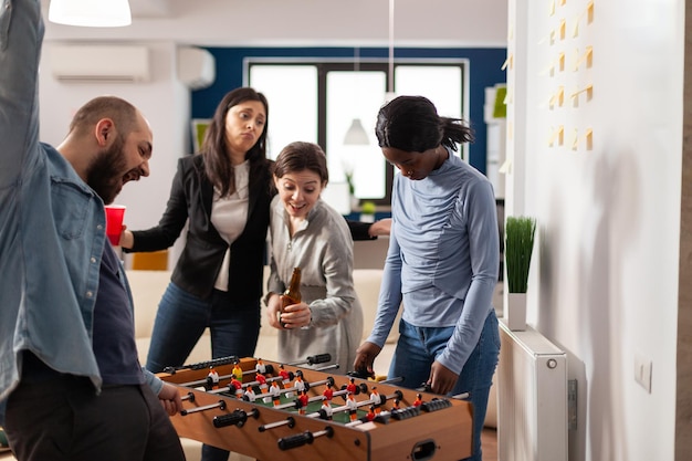 Donna frustrata che perde al biliardino in ufficio, partecipando alla celebrazione delle bevande dopo il lavoro con i compagni di lavoro. Persona che si sente triste per la partita persa, che beve alcol e pizza.