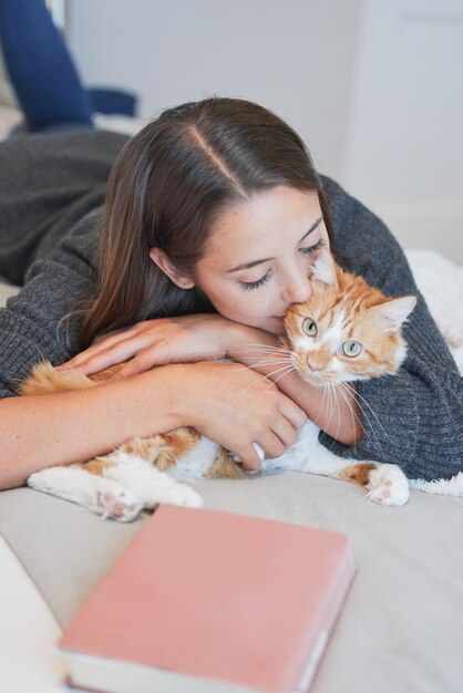 Donna gatto e bacio sul letto in casa per l'amore cura e legame insieme per rilassarsi al mattino ragazza animale domestico e abbracciare carino ginger felino in camera da letto per la connessione giocare e abbracciar in casa