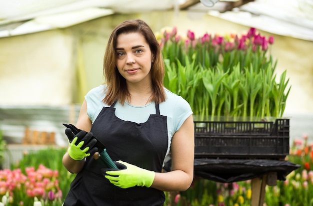 Donna giardiniere con attrezzi da giardino nella serra