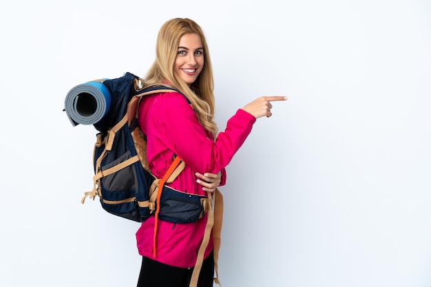 Donna giovane alpinista con un grande zaino isolato dito puntato di lato