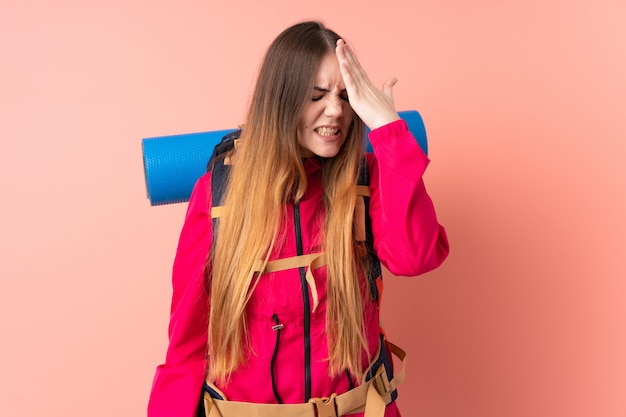 Donna giovane alpinista con un grande zaino isolato sulla parete rosa con dubbi con espressione del viso confuso