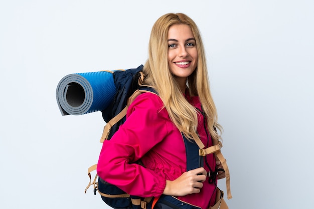 Donna giovane alpinista con un grande zaino sul muro bianco