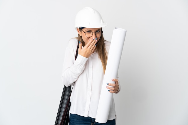 Donna giovane architetto lituano con casco e azienda schemi isolati su sfondo bianco felice e sorridente che copre la bocca con la mano