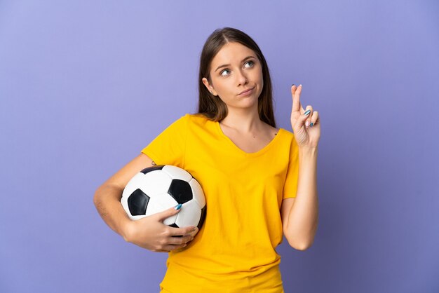 Donna giovane calciatore lituano isolata sul muro viola con le dita che si incrociano e che desiderano il meglio