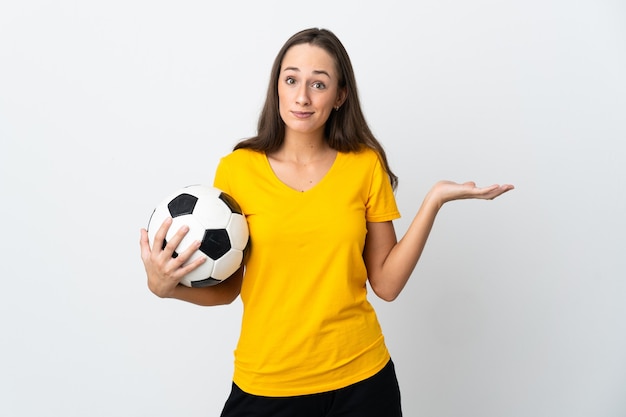 Donna giovane calciatore su sfondo bianco isolato che ha dubbi mentre si solleva le mani