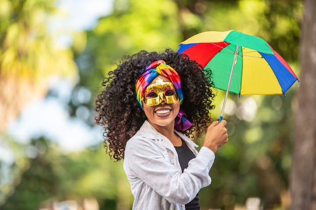 Donna giovane capelli ricci che celebra la festa di carnevale brasiliano con l'ombrello Frevo sulla strada.