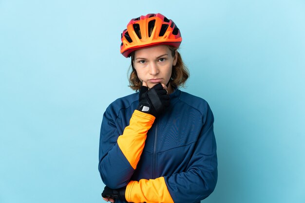 Donna giovane ciclista isolata sul pensiero blu del fondo