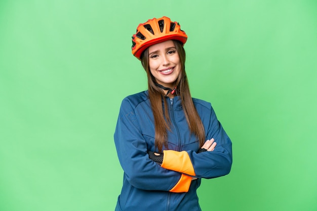 Donna giovane ciclista su sfondo chroma key isolato con le braccia incrociate e guardando avanti