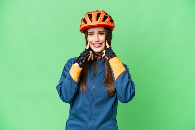 Donna giovane ciclista su sfondo chroma key isolato sorridente con un'espressione felice e piacevole