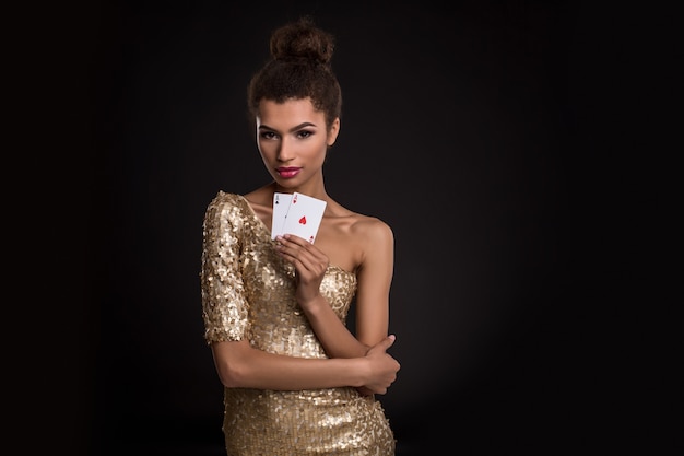 Donna giovane donna vincente in un elegante abito dorato con in mano due assi una combinazione di carte poker d'assi