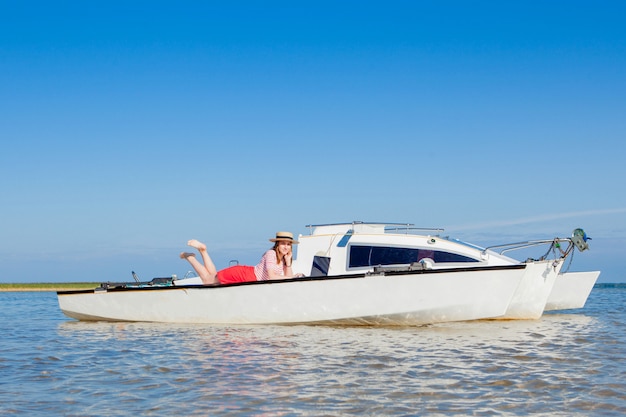 Donna giovane e bella con il computer portatile sulla barca a vela.