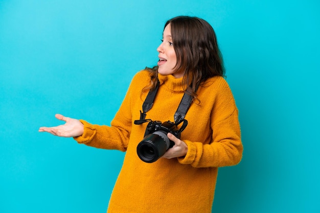 Donna giovane fotografo isolata su sfondo blu con espressione facciale a sorpresa