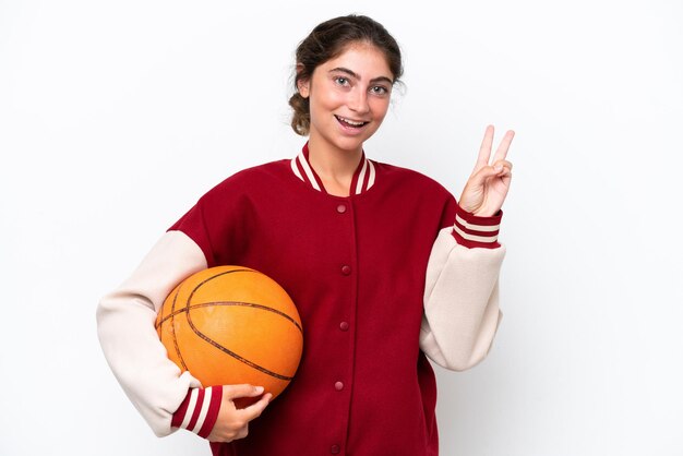 Donna giovane giocatore di basket isolata su sfondo bianco sorridente e mostrando il segno di vittoria