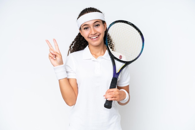 Donna giovane giocatore di tennis isolata su sfondo bianco sorridente e mostrando il segno di vittoria