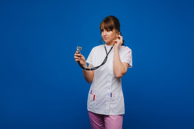 Donna giovane medico con stetoscopio isolato su sfondo blu.