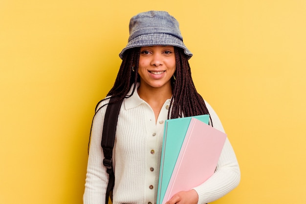 Donna giovane studente afroamericano isolata sulla parete gialla felice, sorridente e allegra