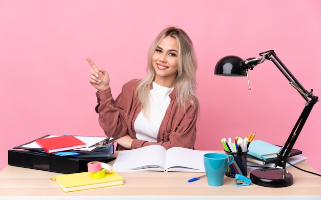 Donna giovane studente che lavora in una tabella che punta il dito verso il lato