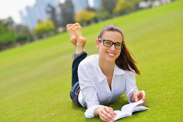 Donna giovane studente che legge un libro e studia nel parco