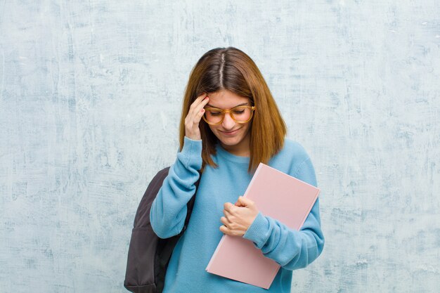 Donna giovane studente che sembra stressata e frustrata, che lavora sotto pressione con mal di testa e turbata da problemi