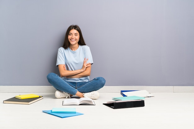 Donna giovane studente con molti libri sul pavimento ridendo