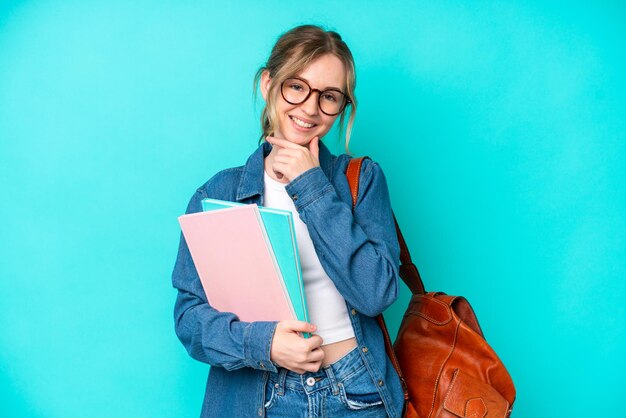 Donna giovane studente isolata su sfondo blu felice e sorridente