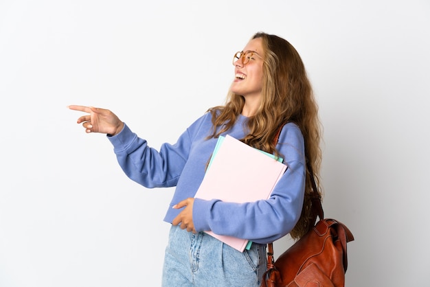 Donna giovane studente isolata sul muro bianco che punta il dito di lato e che presenta un prodotto