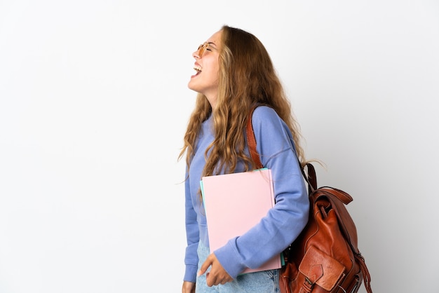 Donna giovane studente isolata sulla parete bianca che ride in posizione laterale