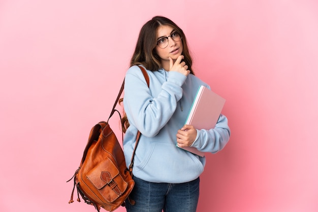 Donna giovane studente isolata sulla parete rosa che ha dubbi