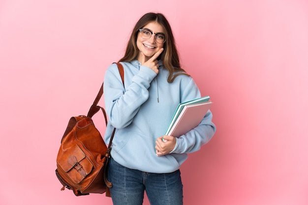 Donna giovane studente isolata sulla parete rosa felice e sorridente