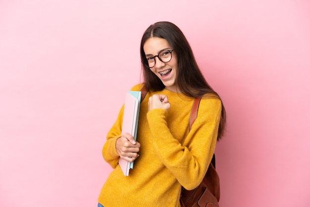 Donna giovane studente su sfondo isolato che celebra una vittoria