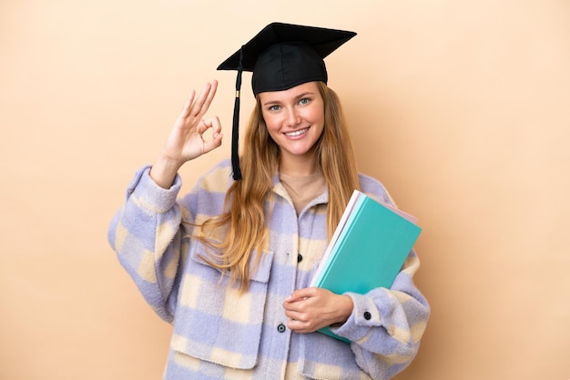 Donna giovane studente su sfondo isolato che mostra segno giusto con le dita