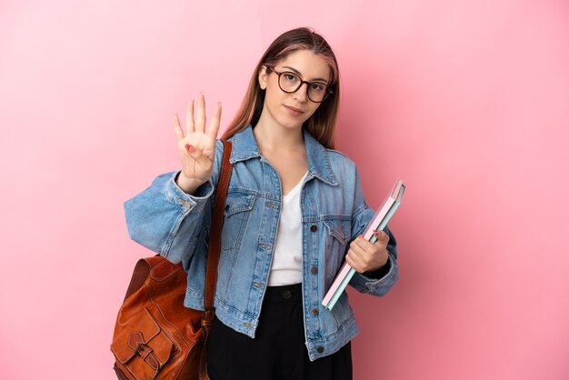 Donna giovane studentessa indoeuropea sul rosa felice e contando quattro con le dita