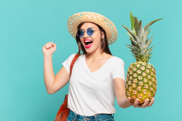 Donna giovane viaggiatore che celebra con successo una vittoria e che tiene un ananas