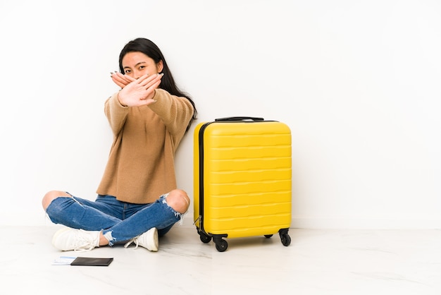 Donna giovane viaggiatore cinese sittting sul pavimento con una valigia