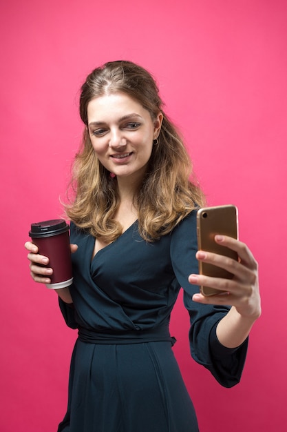 Donna glamour con un drink di caffè su uno sfondo rosa.