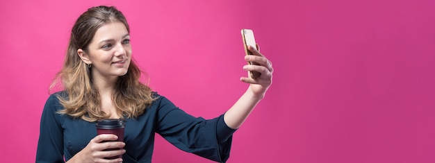 Donna glamour con un drink di caffè su uno sfondo rosa