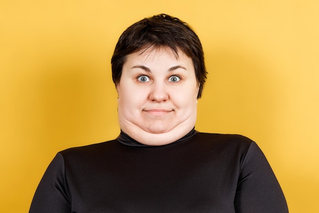 Donna grassa con doppio mento e sguardo pazzo su sfondo giallo Foto di alta qualità