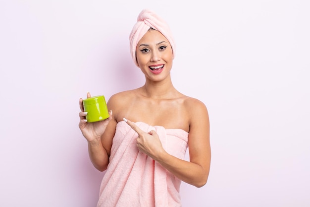 Donna graziosa asiatica che sembra eccitata e sorpresa che indica il lato. maschera per capelli e concetto di cura