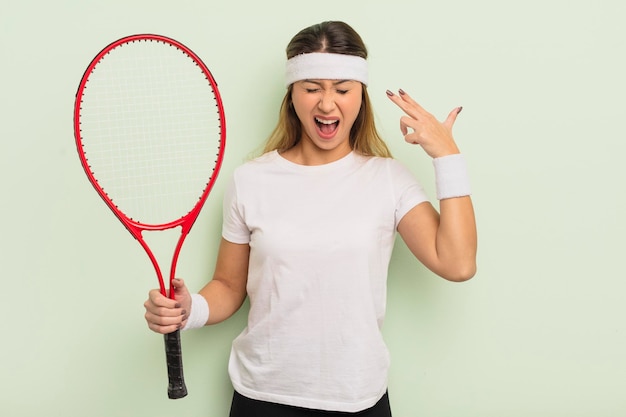 Donna graziosa asiatica che sembra gesto di suicidio infelice e stressato che fa il concetto di tennis del segno della pistola