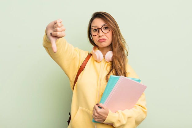 Donna graziosa asiatica che si sente crossshowing pollice verso il concetto di studente universitario