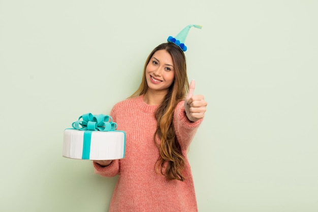 Donna graziosa asiatica che si sente orgogliosa di sorridere positivamente con il concetto di compleanno dei pollici in su