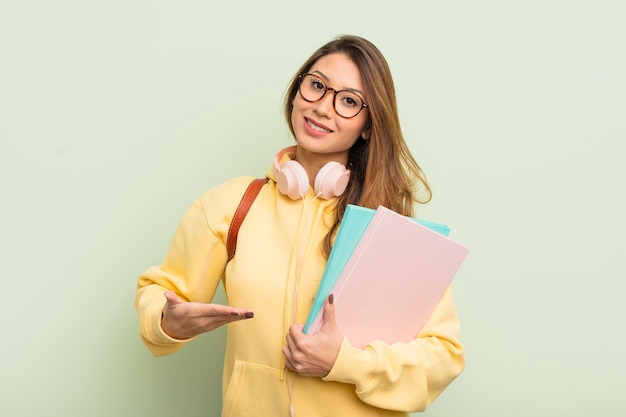 Donna graziosa asiatica che sorride allegramente, sentendosi felice e mostrando un concetto. concetto di studente universitario