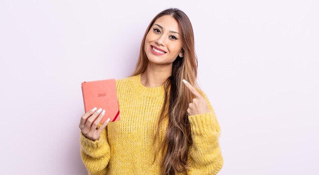 Donna graziosa asiatica che sorride con sicurezza indicando il proprio ampio sorriso. concetto di agenda