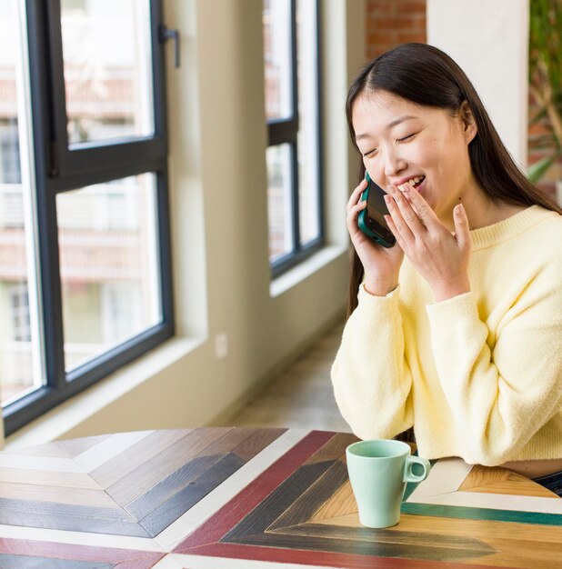 Donna graziosa asiatica che utilizza uno smartphone in una casa fresca