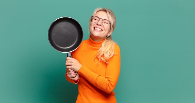 Donna graziosa bionda che impara cucinare con una pentola